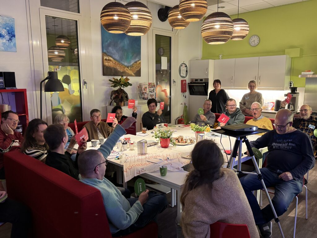 deelnemers steken een groen of rood bordje omhoog als antwoord op een stelling