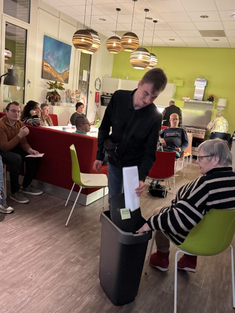 een deelnemer stopt het stembiljet in de stembus