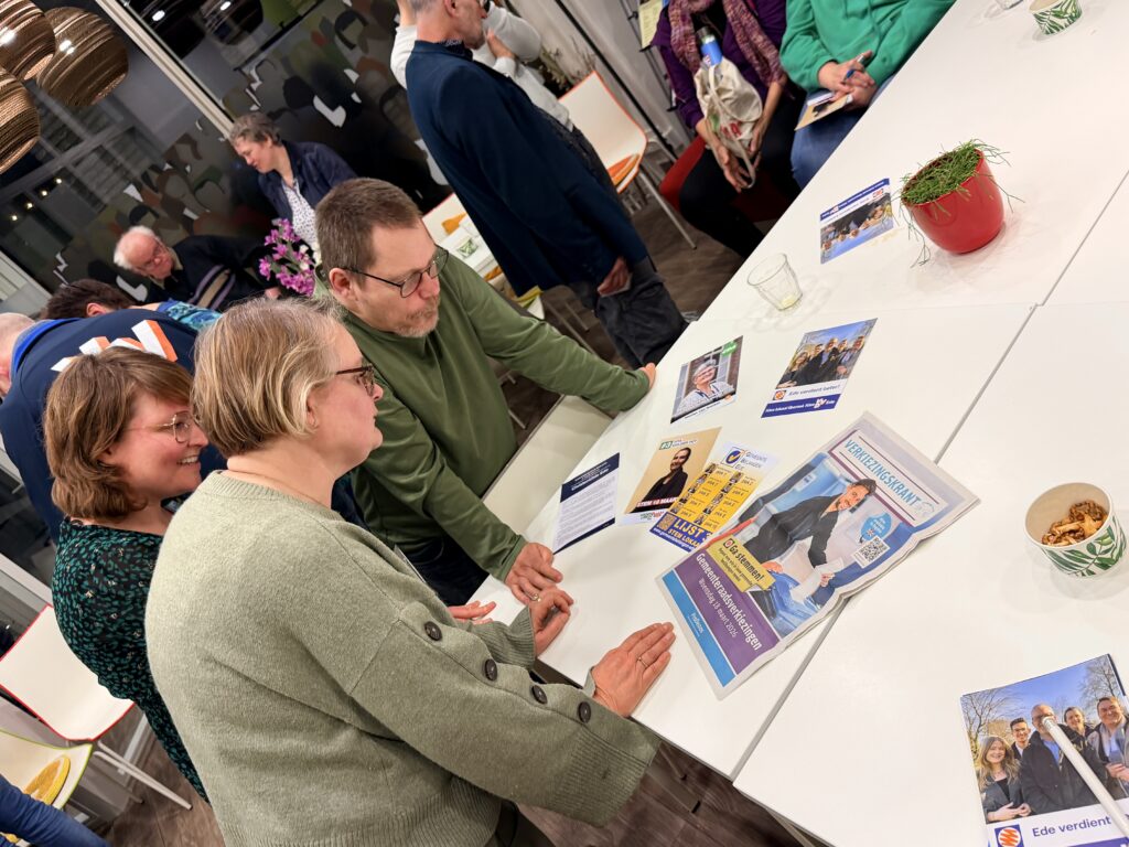 leden van OSE bekijken de verkiezingskrant en flyers van politieke partijen